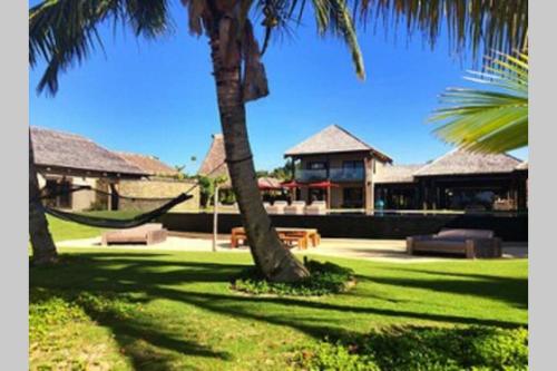 a palm tree and a hammock in front of a house at Villa Takali - CFC Certified in Pacific Harbour