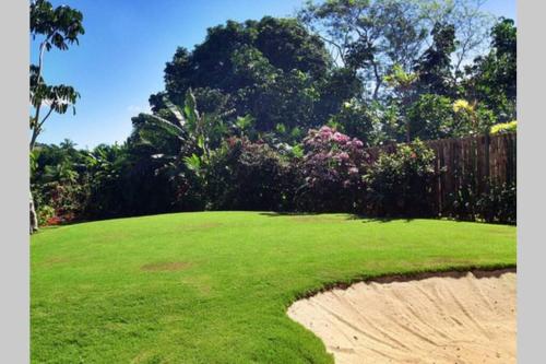 a field of green grass with a fence and trees at Villa Takali - CFC Certified in Pacific Harbour