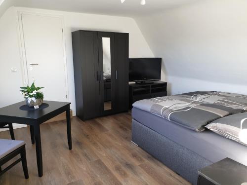 a bedroom with a bed and a table and a television at Ferienwohnung Berger Bocholt in Bocholt