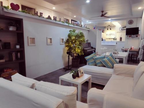 a living room with white couches and a piano at Crossroads Hostel Manila in Manila