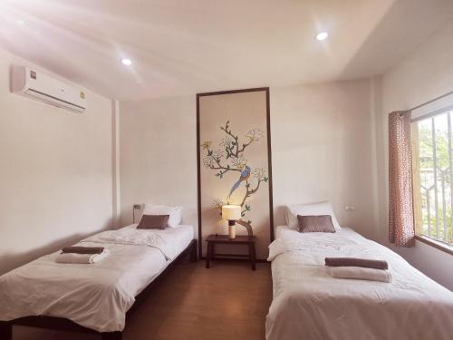 two beds in a room with white walls at Nararin Garden House in Ban Nong Sa