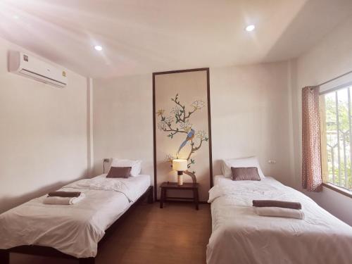 Ban Nong SrahにあるNararin Garden Houseの白い壁の部屋にベッドが2つある