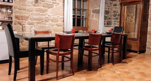 een eettafel met stoelen en een laptop erop bij La Méridienne des Collines in La Motte-de-Galaure
