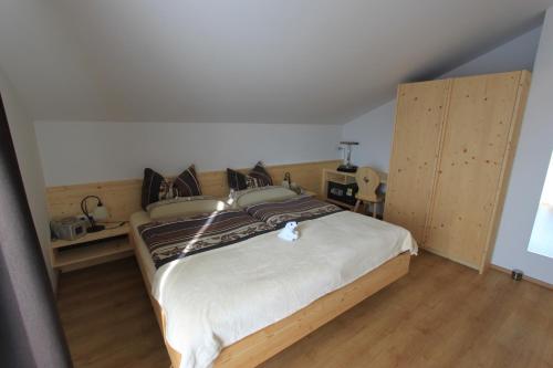 a bedroom with a large bed and wooden floors at Gästehaus Waldrand Garni in Wiesing