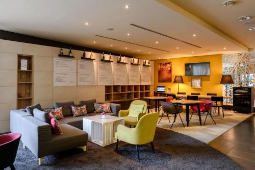 a lobby with a couch and chairs and tables at Mercure Stuttgart City Center in Stuttgart