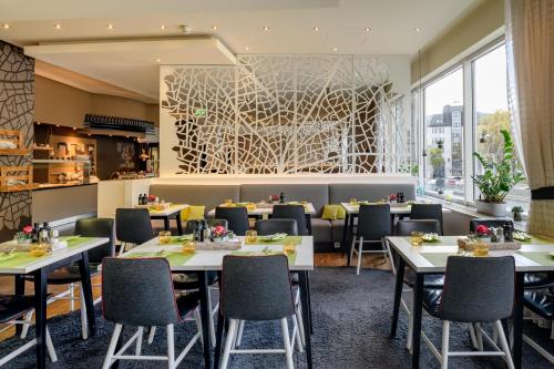 un restaurante con mesas y sillas y una gran ventana en Mercure Stuttgart City Center en Stuttgart