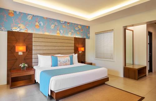 a bedroom with a large bed with a blue wall at Movenpick Resort & Spa Boracay in Boracay