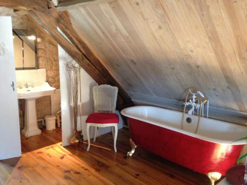 baño con bañera roja y lavamanos en The Cottage, en Hautefort