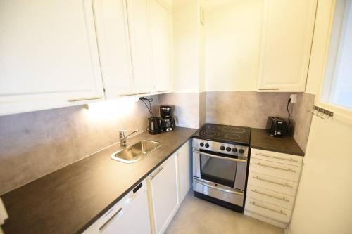 kuchnia z białymi szafkami, kuchenką i zlewem w obiekcie Rental Apartment Patterihaka Suomen Vuokramajoitus Oy w mieście Turku