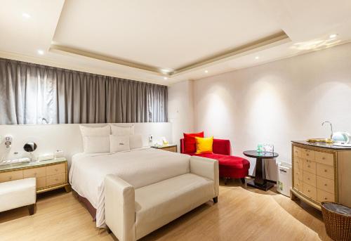 168 Motel-PingZhen في Pingzhen: غرفة نوم بسرير ابيض وكرسي احمر