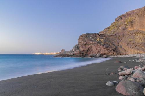 a black beach with rocks and a mountain at Casa Calma Yoga Hostel in Agaete