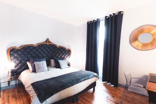 a bedroom with a large bed with black curtains at L'Enclos de Ribains in Aubière