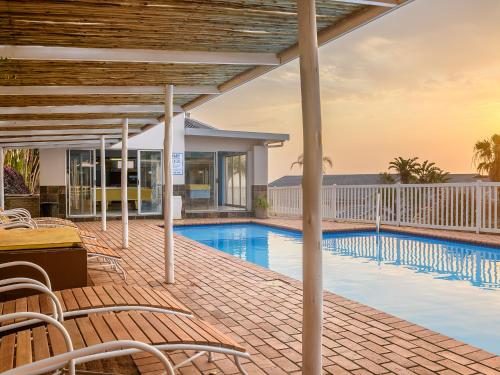 a patio with a swimming pool and chairs next to a building at Illovo Beach Club in Amanzimtoti