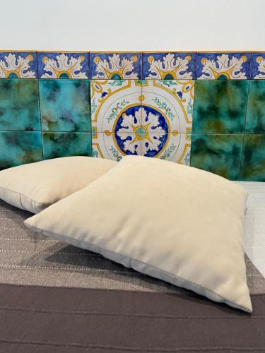 zwei Kissen auf einem Bett vor einer Wand in der Unterkunft Casa vacanze Al porticciolo romantico in Trappeto