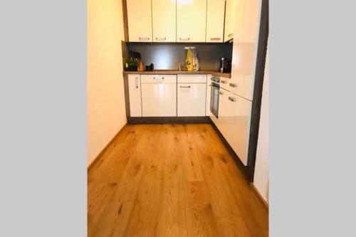 a kitchen with white cabinets and a wooden floor at Your beautiful Homestay in Rheinfelden