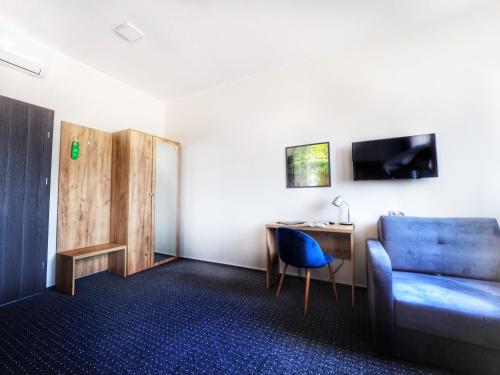a hotel room with a blue couch and a desk at S7 Hotel in Kielce