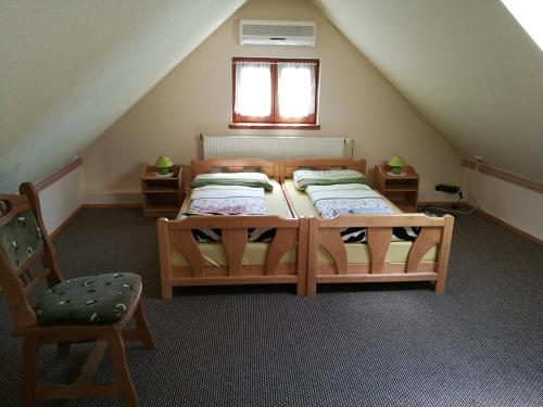 un dormitorio en el ático con 2 camas y una silla en Gergely Vendégház, en Zirc