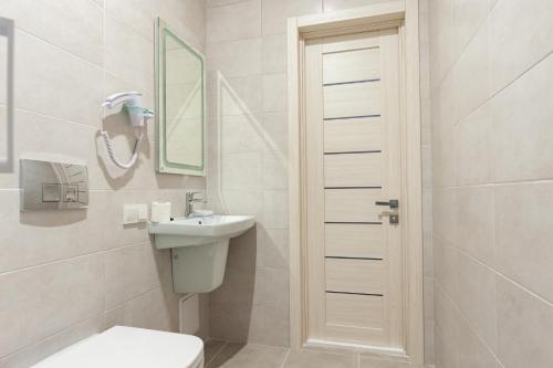 a white bathroom with a toilet and a sink at Hotel Voskresensky in Sumy