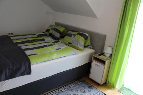 a bed with green and black sheets and pillows at Biobauernhof Höllerbauer in Mönichwald
