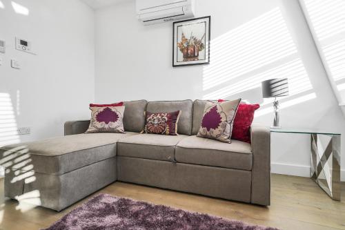 a living room with a gray couch with pillows at City Prime Apartments in London
