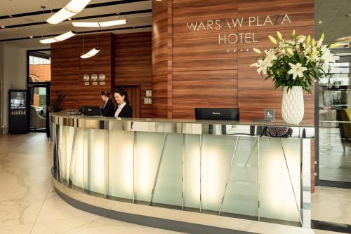 two people sitting at a reception counter in a hotel at Warsaw Plaza Hotel in Warsaw