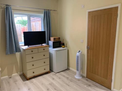 a room with a television on a dresser with a microwave at Southernwood - Wantage Road Studio 1 in Didcot