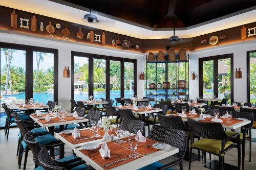 a restaurant with tables and chairs and windows at Movenpick Resort & Spa Boracay in Boracay
