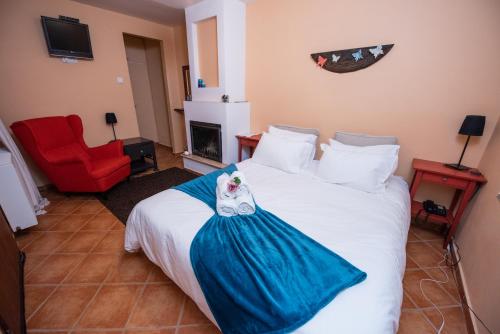 a bedroom with a white bed and a red chair at Archontiko Argyro in Makrinítsa