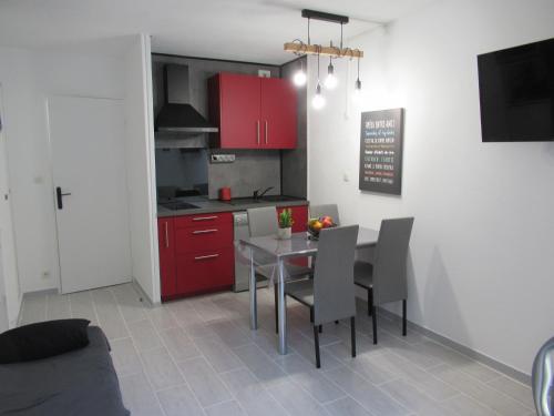 une cuisine avec des armoires rouges et une table et des chaises dans l'établissement La mer à 3 minutes, la clé d'un séjour réussi !, à Saint-Cyr-sur-Mer