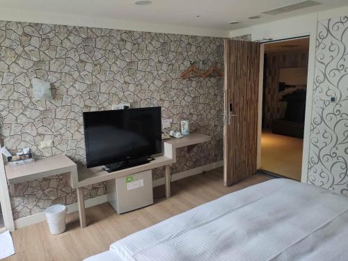 1 dormitorio con TV de pantalla plana en la pared en HengChang Business Hotel, en Keelung