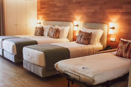 two beds in a hotel room with wooden walls at Cascais City & Beach Hotel in Cascais
