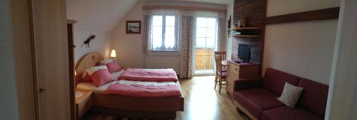 a bedroom with a bed and a couch and a window at Biobauernhof Höllerbauer in Mönichwald
