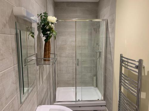 a bathroom with a shower with a toilet and a vase of flowers at Southernwood - Wantage Road Studio 2 in Didcot