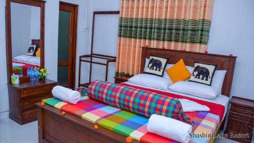 a bedroom with a bed with a colorful blanket at Shashin Lake Resort in Dambulla