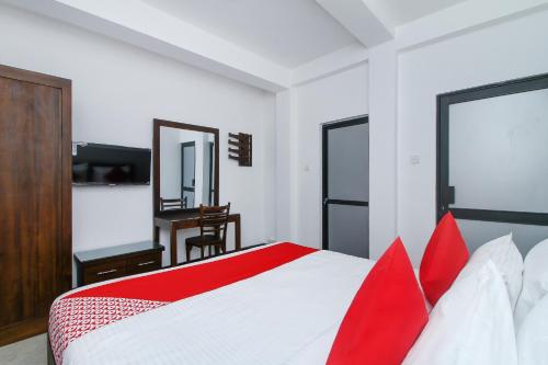 a bedroom with a red and white bed and a desk at Delphin Hotel in Nuwara Eliya