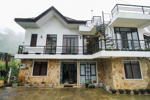 a house with a balcony on top of it at Delphin Hotel in Nuwara Eliya