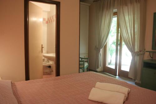 a bedroom with a bed and a bathroom with a window at Hotel Maristella in Cavo