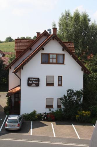 a white building with a car parked in front of it at Hotel & Restaurant Zum Ochsen -Ox Distillery in Hösbach