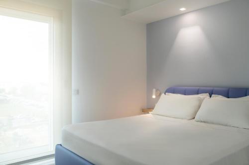 YOUMAMI Suite Hotel في جوليانوفا: سرير ابيض مع مخدات بيضاء ونافذة