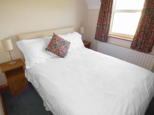 a bedroom with a white bed with a pillow and a window at No 17 Mountain Dale in Tullaghan