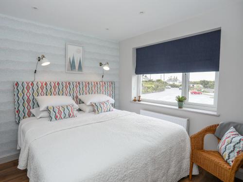 a bedroom with a white bed and a window at Burton Apartment in Trearddur