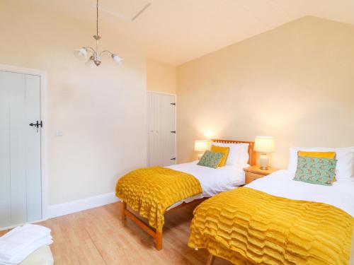 two beds in a room with yellow sheets at The Lodge at Raheengraney House in Cluain na nGall