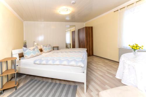 - une chambre avec un grand lit blanc et une table dans l'établissement Gasthof Zum Burgkrug, à Leuchtenberg