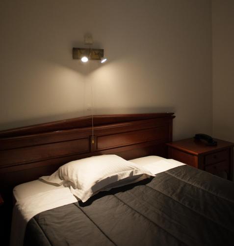 a bedroom with a bed with a wooden headboard at JFK Hotel Zelzate - Gent in Zelzate