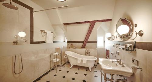 ein Badezimmer mit einer Badewanne, einem Waschbecken und einem Spiegel in der Unterkunft Hotel Schloss Freudental in Allensbach