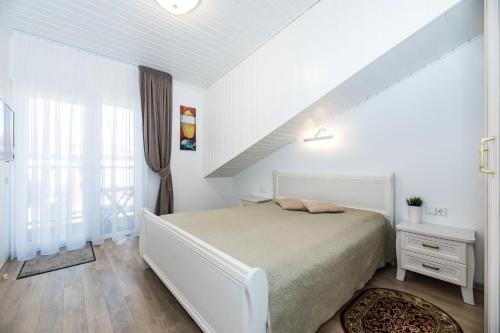 ein weißes Schlafzimmer mit einem Bett und einem Fenster in der Unterkunft Toro apartamentai - Centras in Palanga