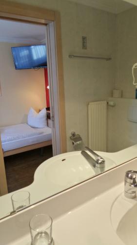 a bathroom with a sink and a mirror and a bed at Hotel Europa in Saas-Fee