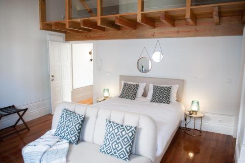 um quarto com uma cama branca e um sofá em GuimaraesIN em Guimarães