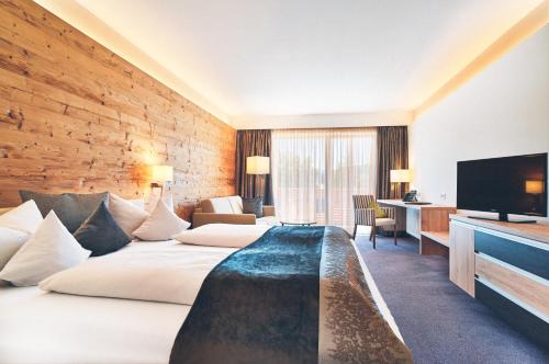 a hotel room with a bed and a flat screen tv at Hotel Eibl-Brunner 4-Sterne-Superior in Frauenau