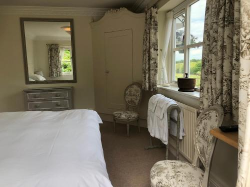 a bedroom with a bed and a mirror and a window at Staggs Cottage in Andover